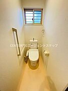 窓があるため換気がしやすいトイレスペースです。手すりが設置されていて安心感があります。シンプルな内装が清潔感を感じさせます。必要な設備がコンパクトにまとまった空間です。