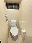 落ち着いた色合いの壁紙で清潔感のあるトイレです。小窓があり換気しやすい環境となっています。ペーパーホルダーも壁付けですっきりとした印象です。温水洗浄機能付き便座が備わっています。