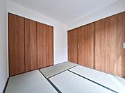 ナチュラルな木目調の建具が印象的な和室です。シンプルな空間が幅広いインテリアに対応します。たっぷり収納できるクローゼットも設置されています。採光もあり明るさが感じられます。