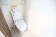 白を基調とした内装で清潔感のあるトイレです。奥には小物を置けるカウンターが設置されています。機能的な設備が整っており空間にゆとりがあります。