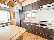 木目調のキッチンが印象的です。自然光が差し込む明るい空間です。収納スペースも豊富で整理しやすいです。