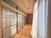 障子戸から柔らかな光が差し込む明るい空間です。長い廊下が奥行きを感じさせます。木の温もりが感じられる落ち着いた雰囲気が魅力です。ガラス窓と障子の組み合わせが和の趣を演出しています。