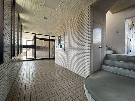 広々としたロビーは白色のタイル壁が印象的です。明るい雰囲気で掲示板も設置されています。大きなガラス扉からたくさんの光が差し込みます。階段もすぐ近くにあり動線も分かりやすいです。清潔感のある空間です。