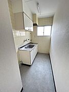 シンプルな壁付キッチンで使いやすい配置です。窓があり自然光が入り風通しも良好です。お掃除がしやすいタイル張りの壁が特徴です。十分な収納スペースも備えています。清潔感のある内装となっています。