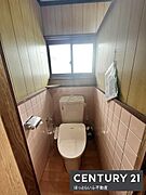 窓付きで換気しやすいトイレです。壁面には清掃がしやすいタイルを採用しています。落ち着いた色合いの内装が特徴です。ペーパーホルダーが設置されています。収納スペースも使いやすい配置です。