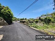 現地前面道路は舗装されており見通しの良い直線的な道が広がっています。周囲には緑が多く落ち着いた雰囲気が感じられます。電線や電柱も整備されており生活に便利な環境です。