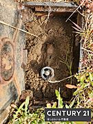 屋外に設置された蓋付きのメーターボックスが見えます。計測機器がしっかりと収納されています。周囲には自然に囲まれた環境が広がっています。手入れが行き届いている印象です。