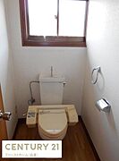 窓付きで明るい雰囲気のトイレです。木目調の床が落ち着いた空間を演出しています。清潔感のあるシンプルな内装です。手洗い付きのタンクが設置されています。