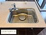 キッチン：広々としたシンクが特徴のキッチンです。使い勝手の良い水栓と付属の水切りラックが設置されています。全体的に清潔感のあるデザインでお手入れも簡単です。周囲もすっきりとした印象です。
