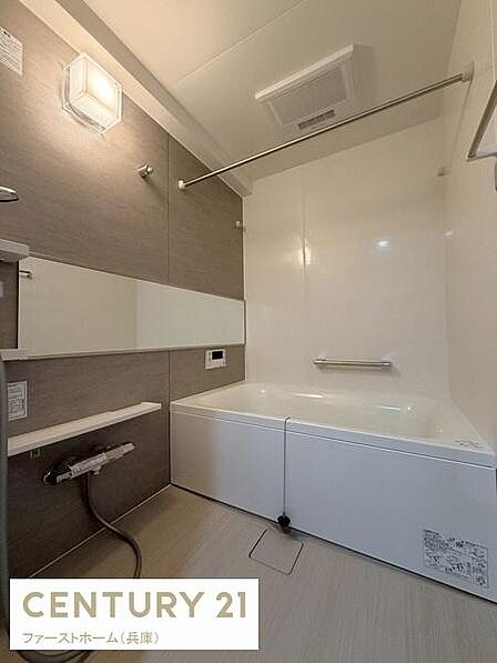 落ち着いた色合いの壁とシンプルなデザインが印象的な浴室です。大きめの鏡が空間を広く見せてくれます。浴槽には手すりが備え付けられており使い勝手を考えた設計です。