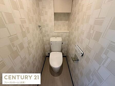 清潔感のある空間でシンプルなデザインが魅力のトイレです。壁紙の柄がアクセントになっており清掃もしやすい印象です。小物の設置スペースもあり使い勝手が良いです。照明や床材の色合いも落ち着いています。