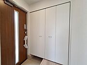 玄関には収納力のあるクローゼットが備え付けられています。扉はシンプルなデザインで空間をすっきりと見せます。フローリングとタイルの段差がアクセントとなっています。室内は明るく清潔感があります。