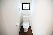 トイレには窓があり換気に配慮された設計です。白を基調とした空間が印象的です。床には温かみのある木目調が使われています。手洗い部分やペーパーホルダーもシンプルにまとまっています。