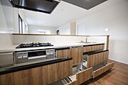 木目調のデザインが落ち着いた雰囲気を演出しています。引き出しが多く収納が充実しています。カウンターがすっきりとしています。キッチン全体が広々とした印象です。