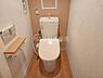 トイレ：温かみのある木目調の床とシンプルな壁色が調和したトイレ空間です。ペーパーホルダーやリモコンが使いやすい位置に設置されています。手洗い付きタンクで利便性にも配慮されています。