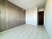 木目調のアクセントクロスが特徴的な洋室です。収納スペースが充実しており片付けもしやすい造りです。明るいフローリングが空間を広く感じさせます。落ち着いた色合いのドアが全体を引き締めています。