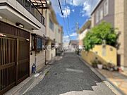 前面道路は舗装されており住宅地ならではの落ち着いた雰囲気が感じられます。周囲には住宅が並び生活利便性の良さがうかがえます。天候も良く明るい空模様が広がっています。