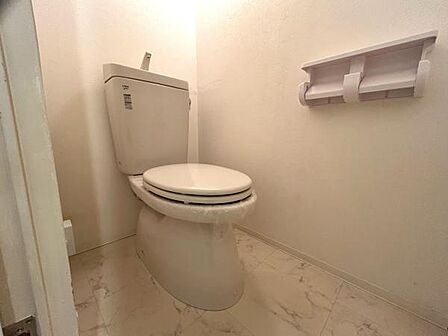 清潔感のあるシンプルなトイレ空間です。壁や床は明るい色合いで統一され清掃のしやすさも魅力的です。ペーパーホルダーも設置され使い勝手に配慮されています。