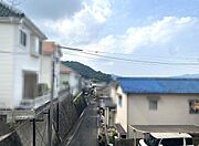 空の広がりを感じられる現地からの眺望。周囲の住宅と山々が見渡せる位置にあり開放感があります。道路に面しており周辺環境がよくわかる景色です。日当たりや空の様子も確認しやすい眺望です。