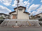 石積みの擁壁の上に建つ高台立地で、周辺との高低差がしっかりと確保されており、道路からの視線が入りにくいプライベート感のある佇まいが特徴的です。