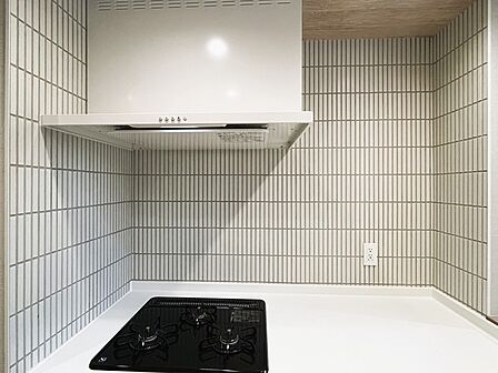 白いタイルと換気扇フード、人口の大理石を白で統一したキッチンデザイン