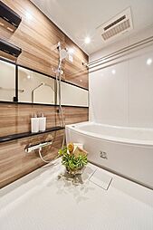 [風呂] 横長ミラーの効果で実際のサイズよりも広がりを感じるバスルームです。光沢感のある木目調のパネルが、より一層くつろぎと高級感を醸し出します。